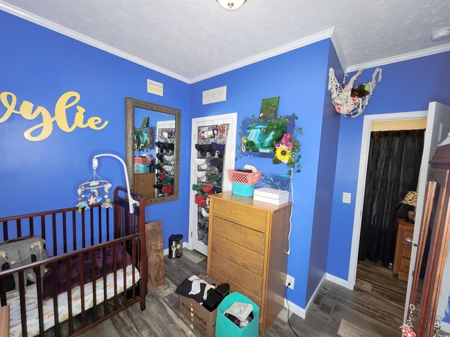 Bedroom with a closet, dark hardwood / wood-style flooring, a nursery area, and ornamental molding | Image 19
