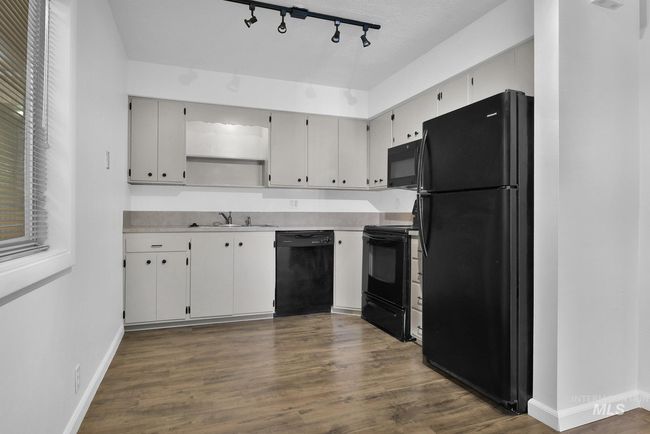 Kitchen with black appliances, rail lighting, dark wood-type flooring, light countertops, and open shelves | Image 12