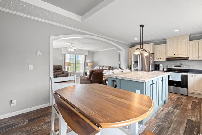 Dining room featuring dark wood-style floors, arched walkways, crown molding, ceiling fan, and recessed lighting | Image 11