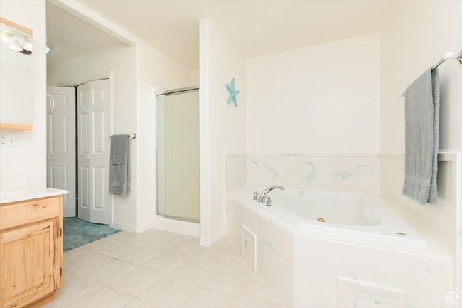 Bathroom featuring a stall shower, a tub with jets, and vanity | Image 30