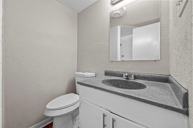 Bathroom with a textured wall and vanity | Image 13