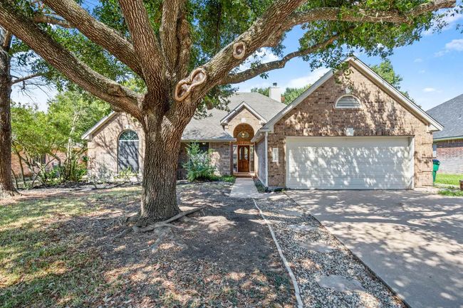 View of front facade featuring driveway, brick siding, a chimney, and an attached garage | Image 4