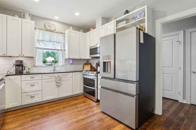 Kitchen with Corian countertops, stainless steel appliances, backsplash, and a sink | Image 13