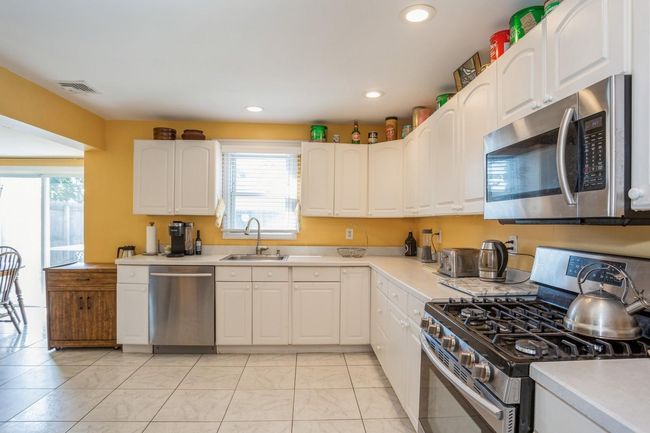 Kitchen with light countertops, visible vents, stainless steel appliances, recessed lighting, and a sink | Image 4