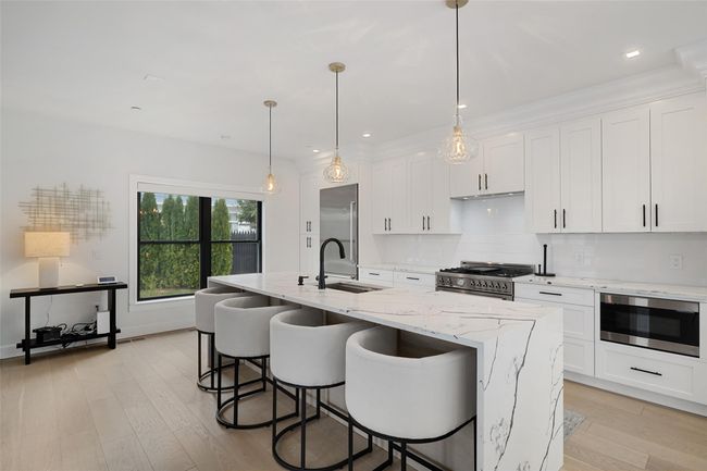 Kitchen with light wood finished floors, appliances with stainless steel finishes, white cabinetry, and a sink | Image 5