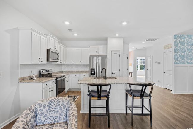 Kitchen with white cabinetry, a sink, appliances with stainless steel finishes, and visible vents | Image 7
