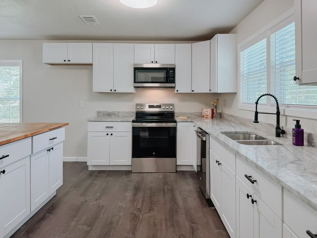 Kitchen with stainless steel appliances, dark wood-style floors, wood counters, and white cabinetry | Image 16