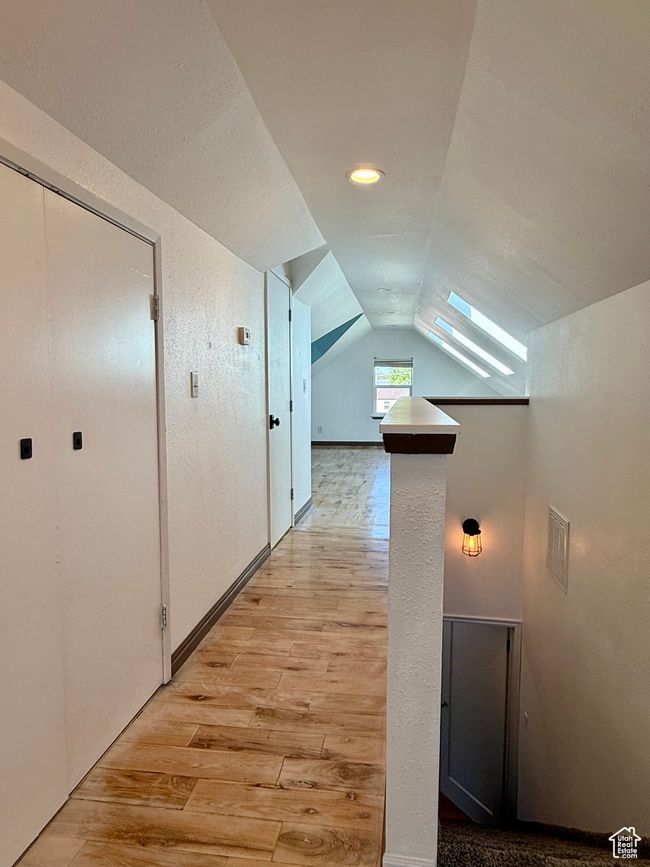Hallway with light wood-style floors and vaulted ceiling | Image 23