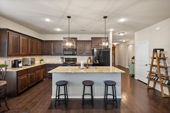 Kitchen featuring dark brown cabinets, an inviting chandelier, a sink, and black appliances | Image 18
