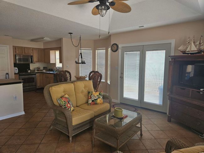 Tiled living room with a textured ceiling, plenty of natural light, and a ceiling fan | Image 4