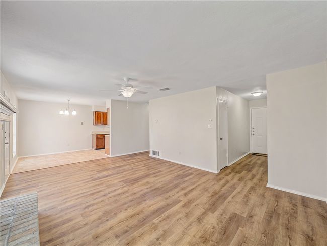 Unfurnished living room with light wood-style flooring, a ceiling fan, a chandelier, and baseboards | Image 5