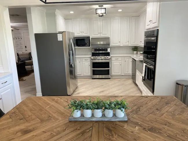 Kitchen with black appliances, white cabinetry, and decorative backsplash | Image 7