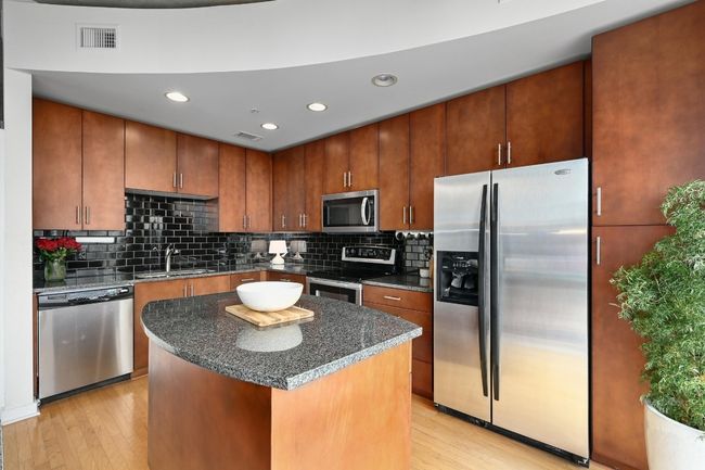 Kitchen with appliances with stainless steel finishes, a sink, light wood finished floors, backsplash, and recessed lighting | Image 7