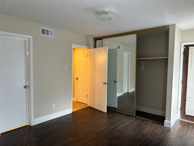 Unfurnished bedroom with dark wood-type flooring and a closet | Image 6