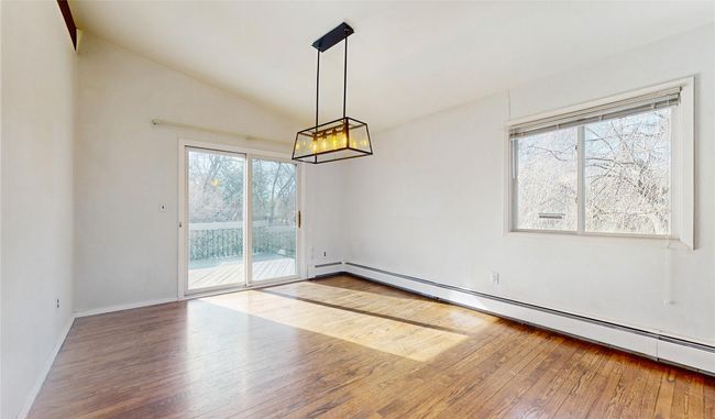 Unfurnished dining area with hardwood / wood-style floors, baseboards, lofted ceiling, a notable chandelier, and baseboard heating | Image 7