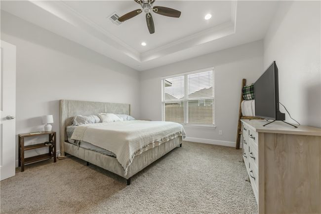 Bedroom with ornamental molding, a raised ceiling, light colored carpet, recessed lighting, and a ceiling fan | Image 7
