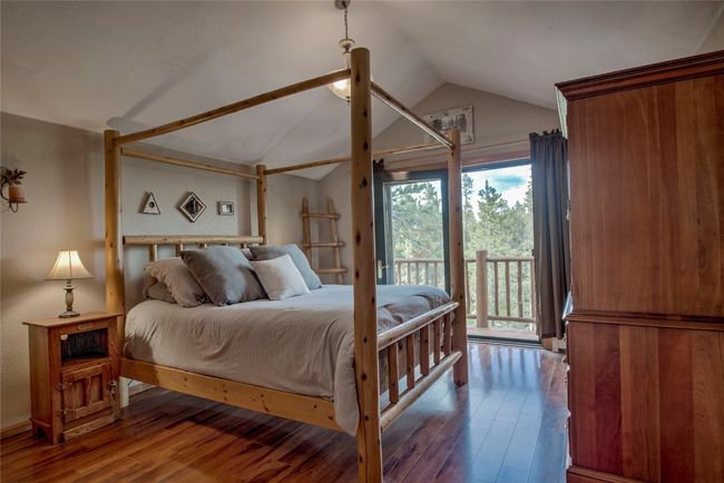 Bedroom with access to outside, vaulted ceiling, wood finished floors, and multiple windows | Image 34