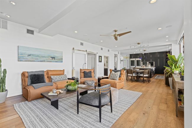 Living area featuring light wood finished floors, visible vents, recessed lighting, and a barn door | Image 11