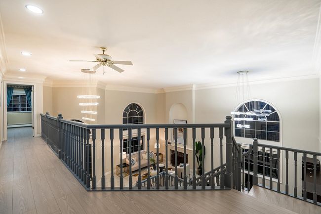 Corridor featuring an upstairs landing, a chandelier, wood finished floors, a baseboard heating unit, and ornamental molding | Image 17
