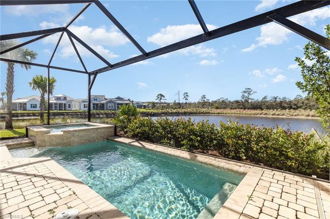 View of pool featuring a lanai, a water view, an in ground hot tub, and a patio | Image 4