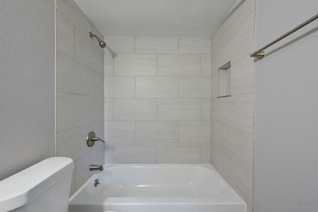Bathroom with a textured wall and shower / bath combination | Image 19