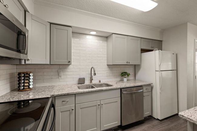 Kitchen featuring a sink, appliances with stainless steel finishes, dark wood finished floors, backsplash, and ornamental molding | Image 9