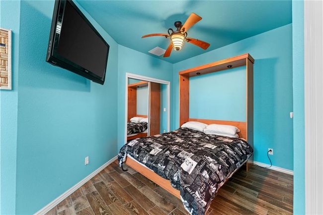 Bedroom with dark wood-type flooring, ceiling fan, visible vents, and baseboards | Image 52