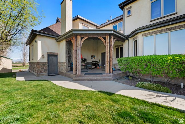 Rear view of house featuring a patio, stucco siding, stone siding, and a lawn | Image 8