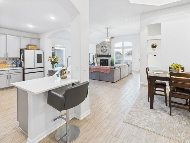 Kitchen featuring freestanding refrigerator, light wood finished floors, arched walkways, a ceiling fan, and vaulted ceiling | Image 13
