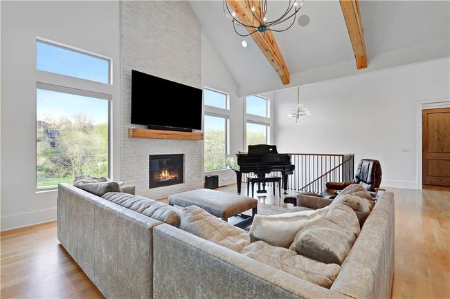 Living room with light wood finished floors, a notable chandelier, high vaulted ceiling, beamed ceiling, and a fireplace | Image 11
