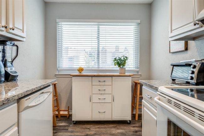 Kitchen featuring white appliances, healthy amount of natural light, dark wood-type flooring, and a textured wall | Image 10