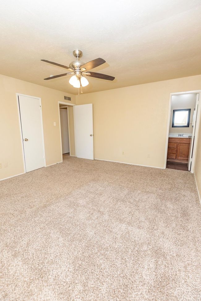 Unfurnished bedroom with carpet flooring, connected bathroom, and ceiling fan | Image 12