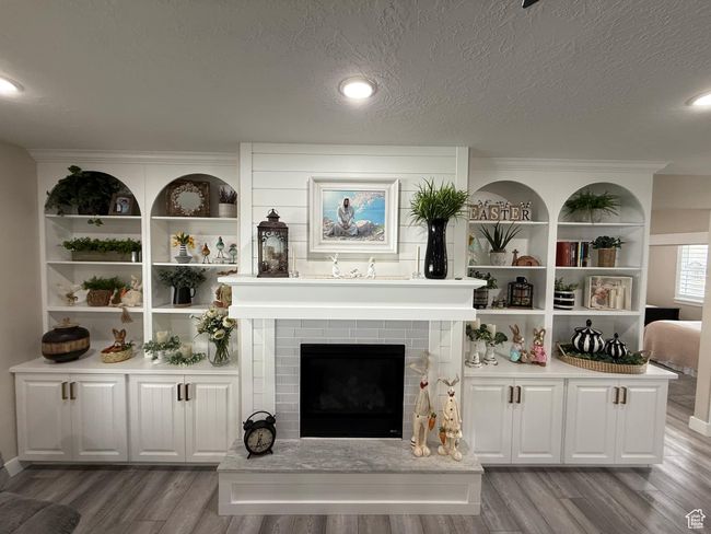 Living area featuring a textured ceiling, wood finished floors, and a brick fireplace | Image 12