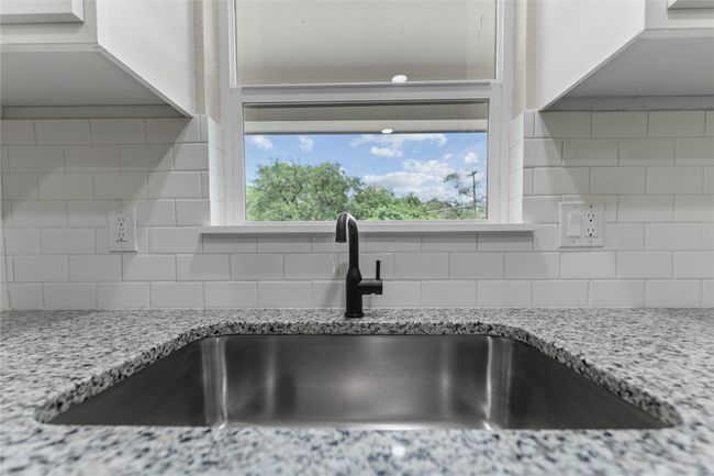 Kitchen view of a sink, tasteful backsplash, and light stone counters | Image 6