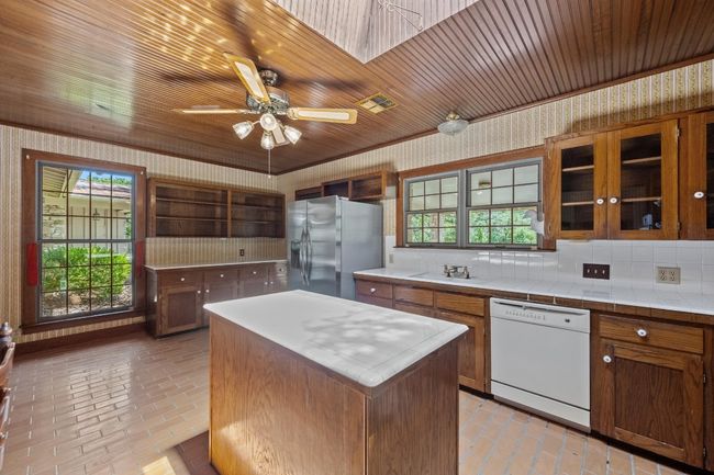Kitchen with dishwasher, stainless steel fridge, wallpapered walls, open shelves, and plenty of natural light | Image 14