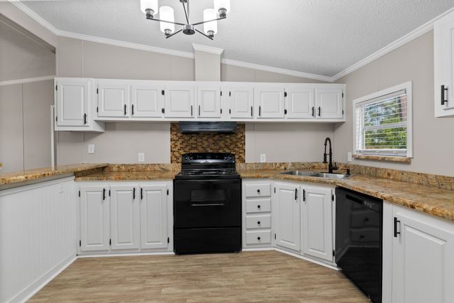 Kitchen featuring black appliances, under cabinet range hood, vaulted ceiling, light wood finished floors, and a chandelier | Image 18