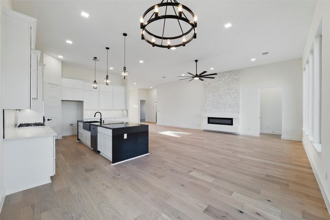 Kitchen featuring ceiling fan with notable chandelier, a sink, light wood-style floors, dishwasher, and white cabinets | Image 27