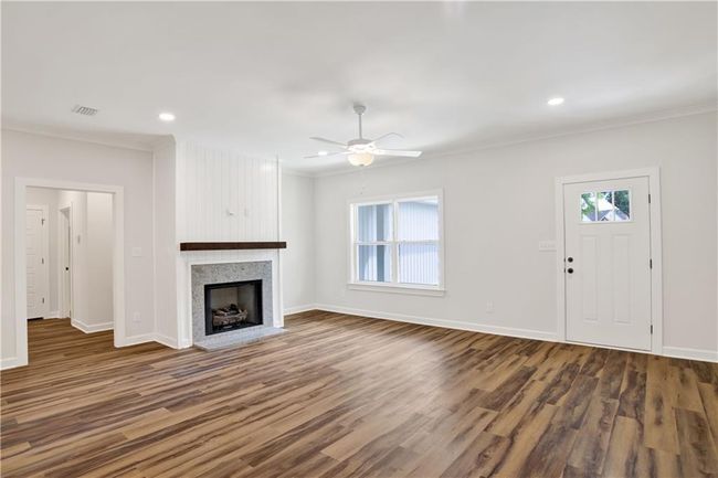 Unfurnished living room with a ceiling fan, baseboards, visible vents, and ornamental molding | Image 11