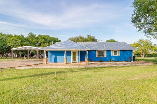 Ranch-style home featuring a carport, a front yard, and metal roof | Image 7