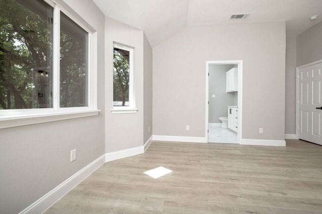 Unfurnished bedroom featuring vaulted ceiling, wood finished floors, and ensuite bath | Image 34