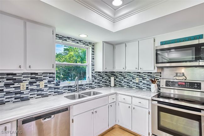 Kitchen featuring appliances with stainless steel finishes, light countertops, backsplash, white cabinets, and recessed lighting | Image 16