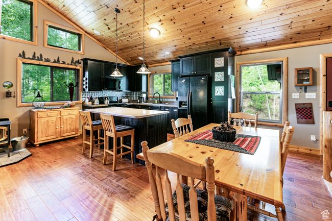 Dining room with wooden ceiling, light wood finished floors, plenty of natural light, high vaulted ceiling, and a wood stove | Image 11