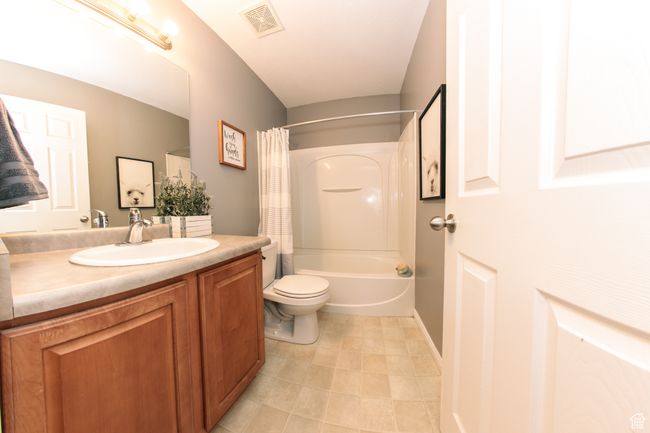 Bathroom featuring a shower/bath combination with curtain, toilet, vanity, and a full bath with tile flooring | Image 14