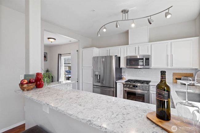 Eating bar with quartz countertop and new lighting and appliances in the backround | Image 17
