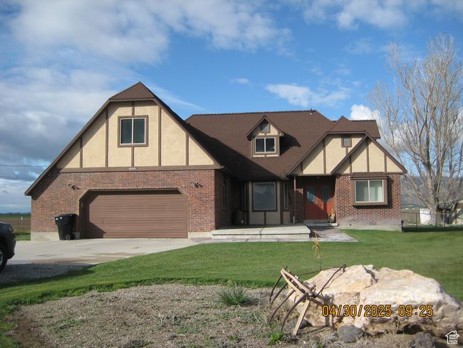 Tudor home featuring a garage, brick siding, driveway, and a front yard | Image 20