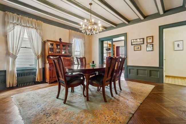 Dining room with beamed ceiling, a crystal chandelier, and wainscoting | Image 9