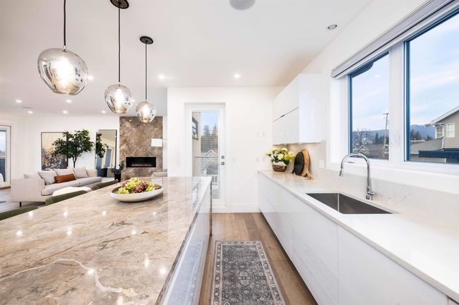 Kitchen featuring modern cabinets, light wood-style flooring, a sink, white cabinetry, and a premium fireplace | Image 10