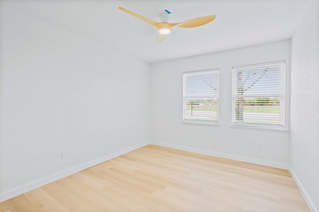 Empty room with light wood-style floors and ceiling fan | Image 25