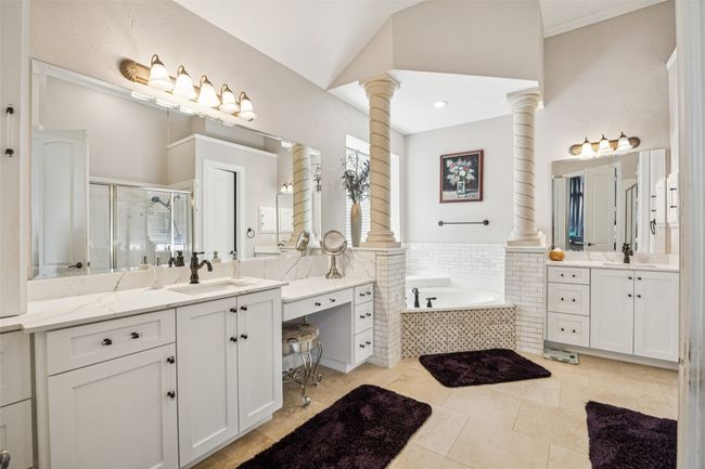 Bathroom with decorative columns, a shower stall, two vanities, a bath, and tile patterned flooring | Image 23