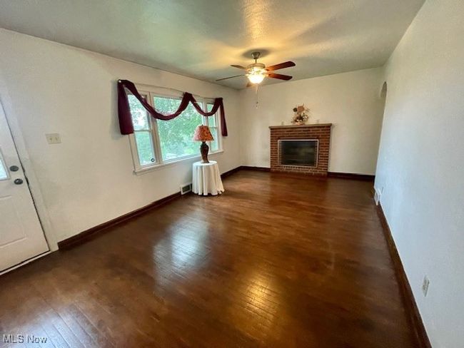 Living room featuring hardwood / wood-style flooring, baseboards, ceiling fan, and a brick fireplace | Image 8